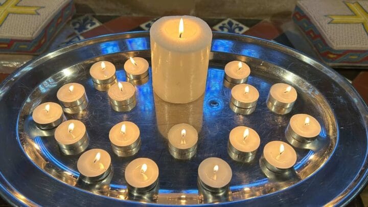 Picture of a pillar candle surrounded by tea lights, lit in remembrance of babies at the Service of Remembrance for Pregnancy and Baby Loss