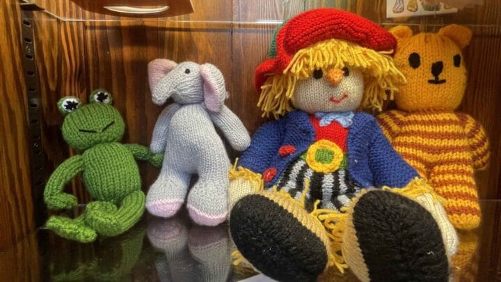 A picture of some locally handmade knitted toys, a frog, elephant, scarecrow and tiger, for sale in the church shop