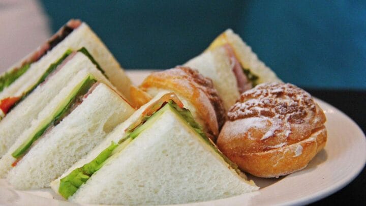 A picture of some sandwiches two small cakes on a plate